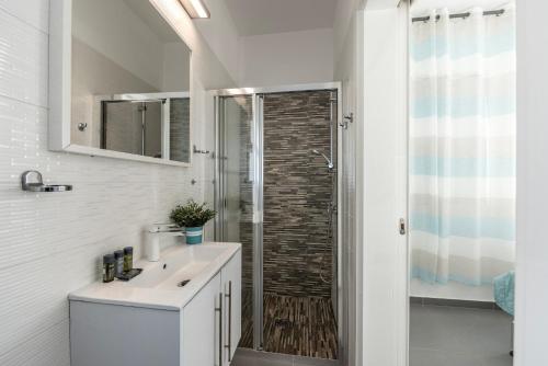 a white bathroom with a shower and a sink at Protaras Villa Alina in Protaras