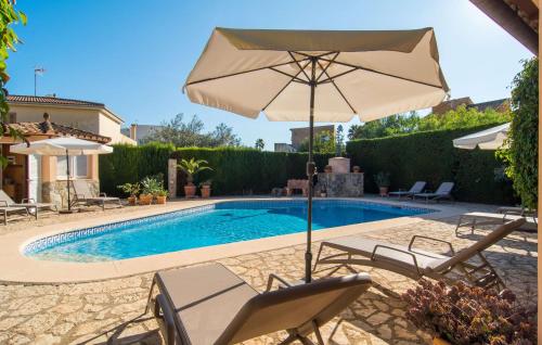 a swimming pool with an umbrella and chairs next to a pool at Casa Romantica De Sa Coma in Sa Coma