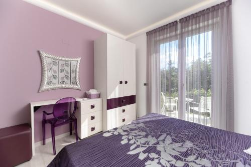 a bedroom with a purple bed and a desk and a window at Villa Luce in Labin