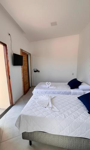 two beds in a white room with a television at Chalé dos Anjos in Fortim