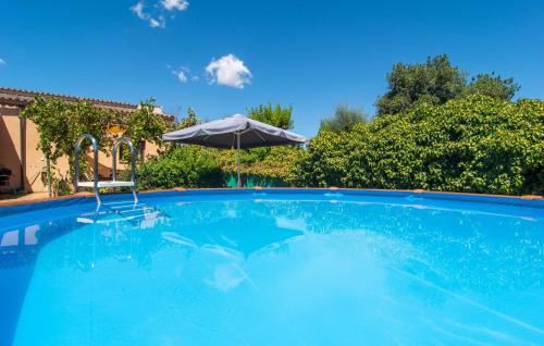 a large blue swimming pool with an umbrella at Cas Nets in Llucmajor