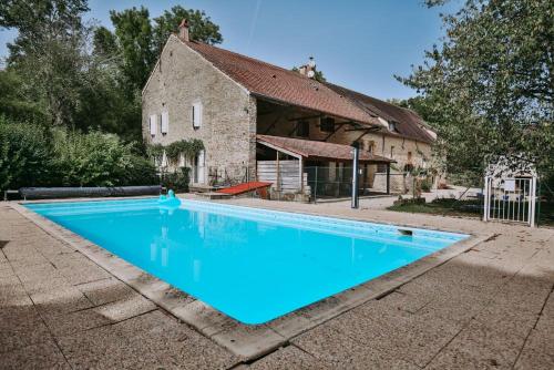 a large blue swimming pool in front of a building at Moulin de Vézelay - Maison d'hôtes in Fontenay-près-Vézelay
