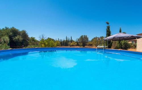 a large blue swimming pool with an umbrella at Cas Nets in Llucmajor