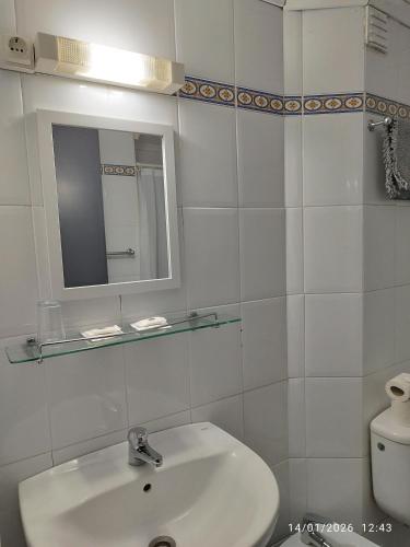 a bathroom with a sink and a mirror and a toilet at Alojamento Central I - Funchal in Funchal