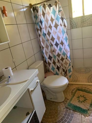 a bathroom with a toilet and a shower curtain at Fazenda Shalom in Tucano