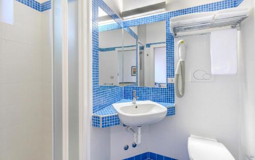 a blue tiled bathroom with a sink and a toilet at Hotel Brig in Cattolica
