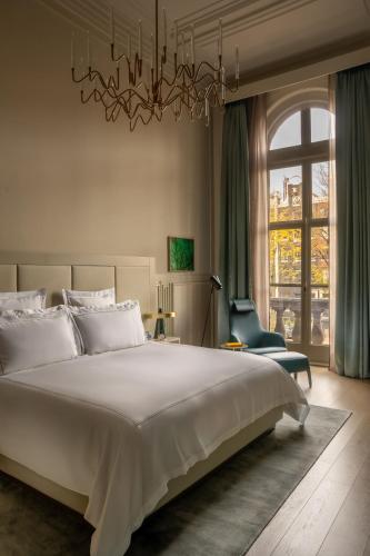 a bedroom with a large bed and a chandelier at Rosewood Amsterdam in Amsterdam