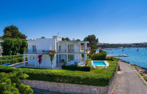 a white house with a swimming pool next to the water at Esperanza in Portocolom