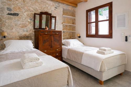 a bedroom with two beds and a dresser and a mirror at Rastoni 1928 Heritage Residence in Egina