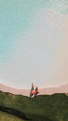 two people sitting on the sand near the water at Böden Hotel & Spa, AKEN SOUL in Villa General Belgrano