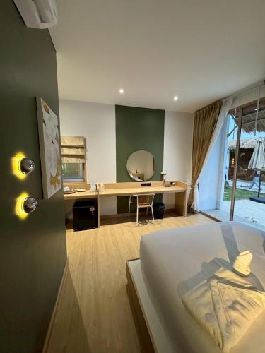 a bedroom with a bed and a desk with a mirror at The Pool House Koh Lanta in Ko Lanta