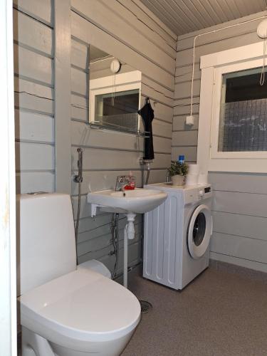 a bathroom with a toilet sink and a washing machine at Villa Irjala in Oulu