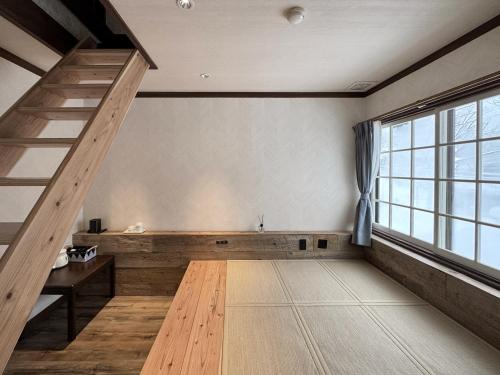 an empty room with a staircase and a large window at Apricot Pension in Hakuba