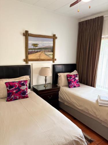 a bedroom with two beds and a table with a lamp at Alendo Apartments in Johannesburg