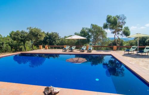 a blue swimming pool with chairs and umbrellas at S'alzinar Gran in Artá
