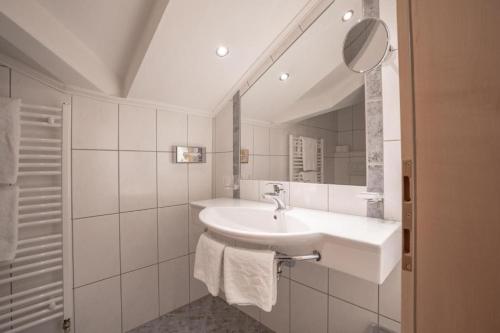 un bagno bianco con lavandino e specchio di Petit Madlein a Ischgl