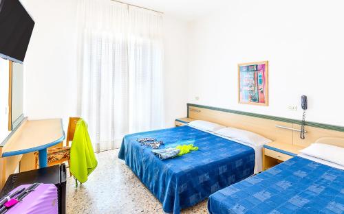 a hotel room with two beds and a desk at Hotel Brig in Cattolica