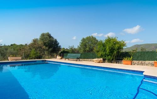 a blue swimming pool with a bench and trees at Sa Plana Port Nou in Cala Millor