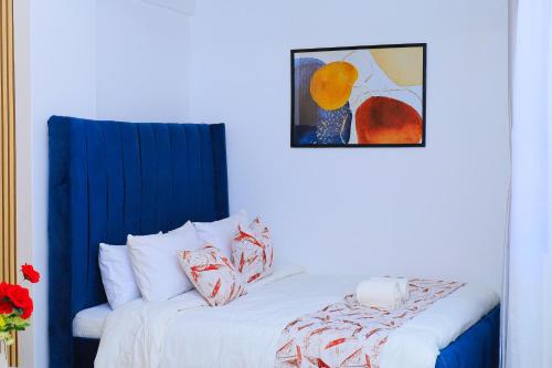 a bedroom with a white bed and a painting on the wall at Naivera Membly Star Heights in Ruiru
