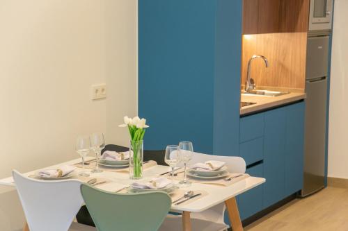 a table with glasses and flowers on it in a kitchen at Apartamentos ÍCARO in Plasencia