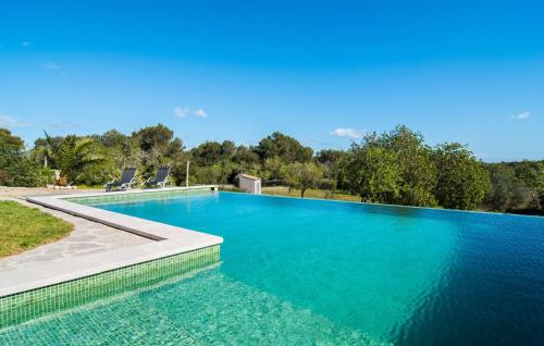 a swimming pool with blue water and two chairs at S'oratge in Artá