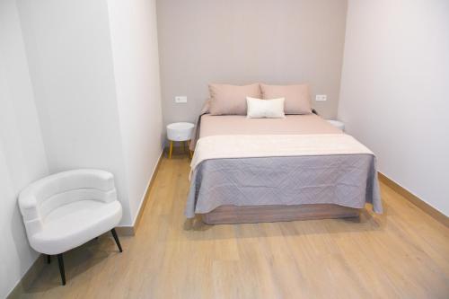 a small bedroom with a bed and a chair at Apartamentos ÍCARO in Plasencia