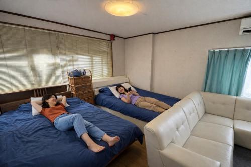 two women laying on beds in a living room at Rooftop Camping Nagasaki-遊べるホステル-Seven-eleven3min in Nagasaki