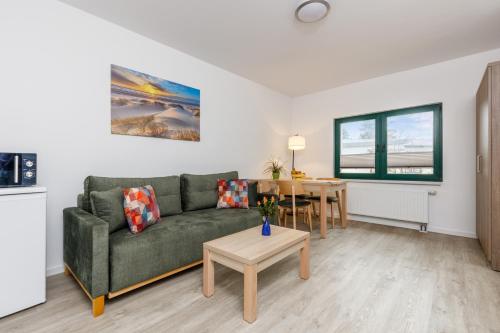 a living room with a green couch and a table at Feriendorf Strandgut in Altenkirchen