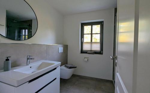 a white bathroom with a sink and a mirror at Ferienhaus Ovis Natur, Ruhe und Erholung in der Lüneburger Heide, Hunde willkommen in Winsen