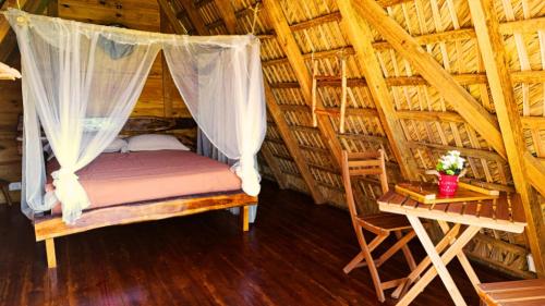 a bed in a thatched room with a table at Eco Lodges Chalets Tropicales Playa Macao in Punta Cana