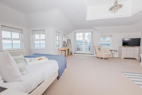 a white bedroom with a bed and a tv at The Tide House in St Ives