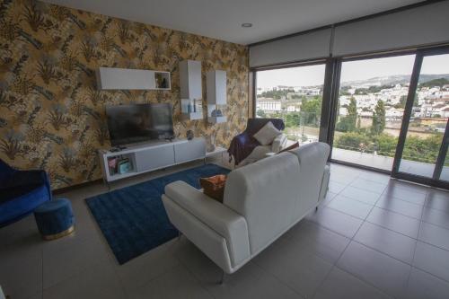 a living room with a white couch and a television at Casa do Pessegueiro in Mirandela