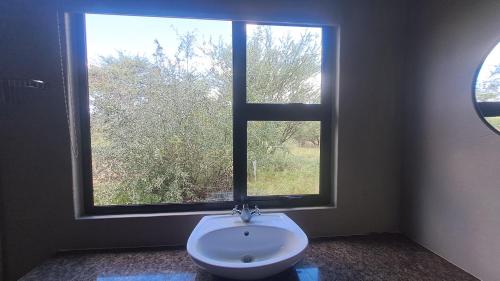 a bathroom with a toilet and a large window at The Spot at Ghanzi in Khemsbok