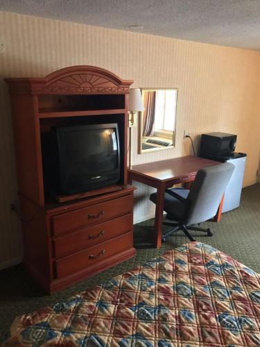 a hotel room with a desk and a tv and a bed at Home Town Inn in Flint