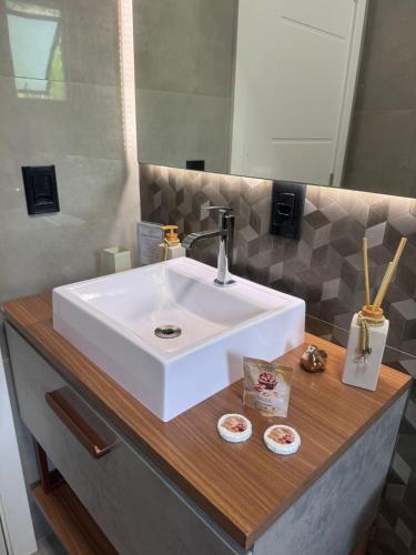 a bathroom with a white sink and a mirror at Villa Pomerode Hospedagem - Suítes com conforto e aconchego conectados com a Natureza in Pomerode