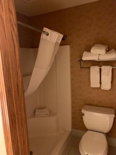 a bathroom with a toilet and a shower with towels at Country Inn & Suites by Radisson, Lincoln North Hotel and Conference Center, NE in Lincoln