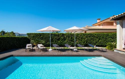 a swimming pool with chairs and umbrellas next to a house at Montelago in Alcudia