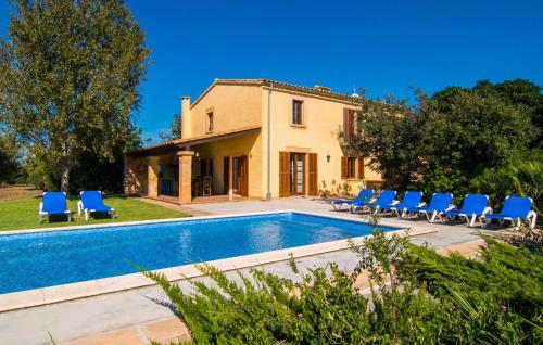 a villa with a swimming pool and blue chairs at Can Bernat in Cala Mendia