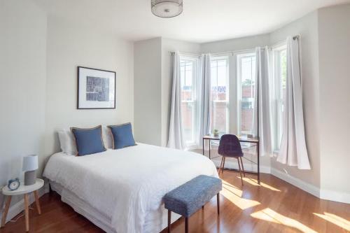 a white bedroom with a bed and a desk at Jennifer's Modern Federal Hill Apt w Private Deck in Providence