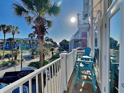 a balcony with two chairs and a palm tree at Gulf Place Spires #7B - Rum Cake in Santa Rosa Beach