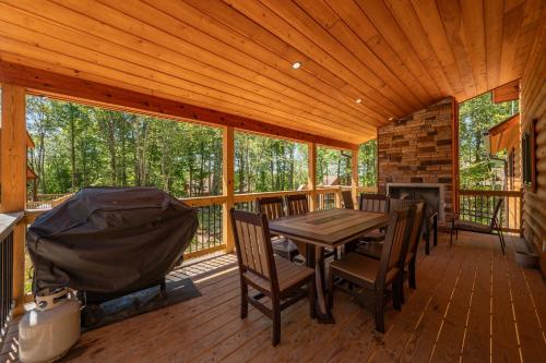 a porch with a wooden table and chairs and a fireplace at Aspen Summit by Railey Vacations in McHenry