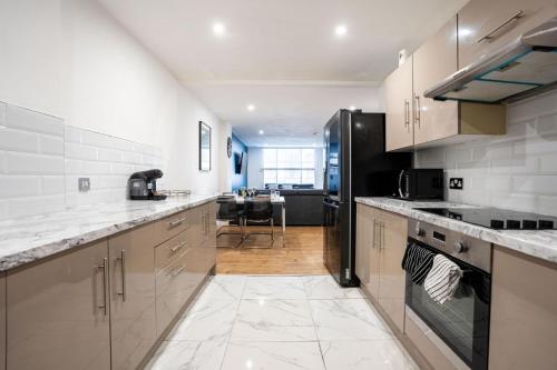 a kitchen with white counter tops and a black refrigerator at Stylish Modern Apartment in the heart of the city in Manchester