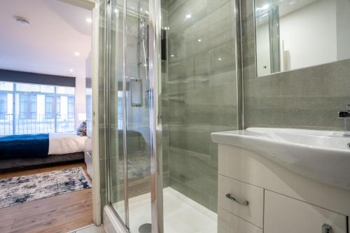 a bathroom with a glass shower and a sink at Stylish Modern Apartment in the heart of the city in Manchester