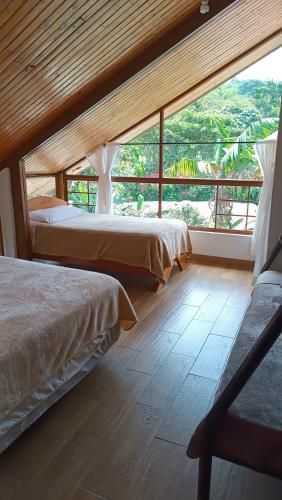 two beds in a room with a large window at Mindo Suites - Rufous in Mindo