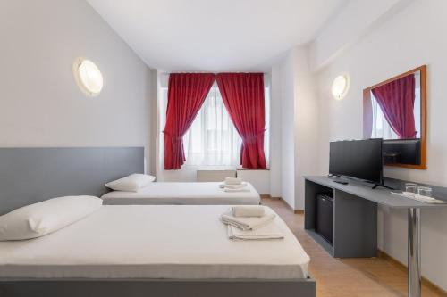 ein Zimmer mit zwei Betten und einem Schreibtisch mit Fernseher in der Unterkunft Elizeu Hotel in Bukarest