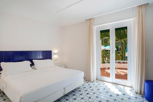 a white bedroom with a bed and a sliding glass door at Hotel Continental Ischia in Ischia Town