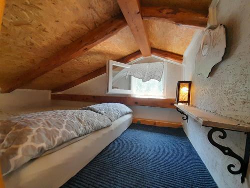 a small attic room with a bed and a window at A tiny sea home in the wilderness in Vis