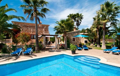 a swimming pool in front of a house with palm trees at Can Lopez Vara in Campos