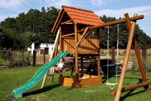 a young girl sitting on a slide in a play house at Na Samotě Ve Srubu in Plzeň