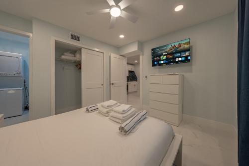 a white bedroom with a bed and a tv on the wall at Three Tides Vacation Rentals in Clearwater Beach